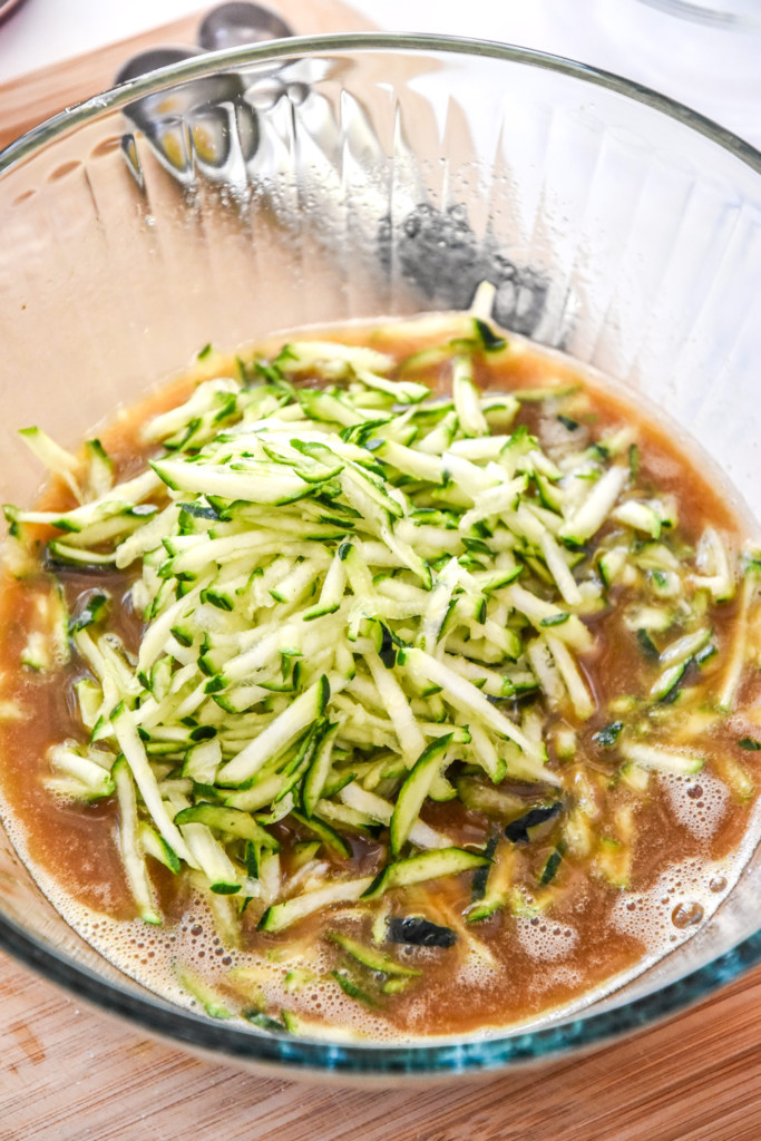 shredded zucchini on top of the wet ingredients for the cinnamon raisin zucchini coffee cake.