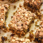 cinnamon raisin zucchini coffee cake cut into pieces on parchment paper.