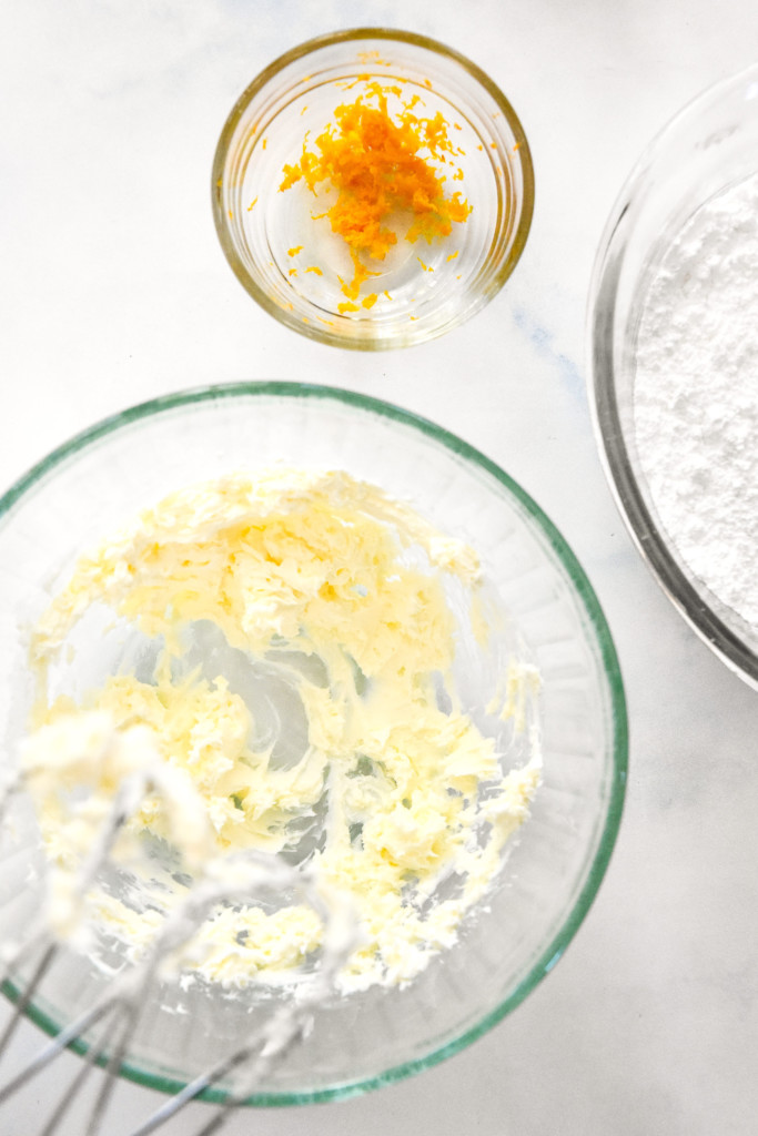 beating the butter and cream cheese together in a glass bowl.