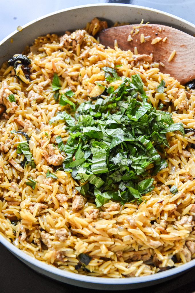 chopped basil on top of a pan of freshly made ground turkey zucchini orzotto.