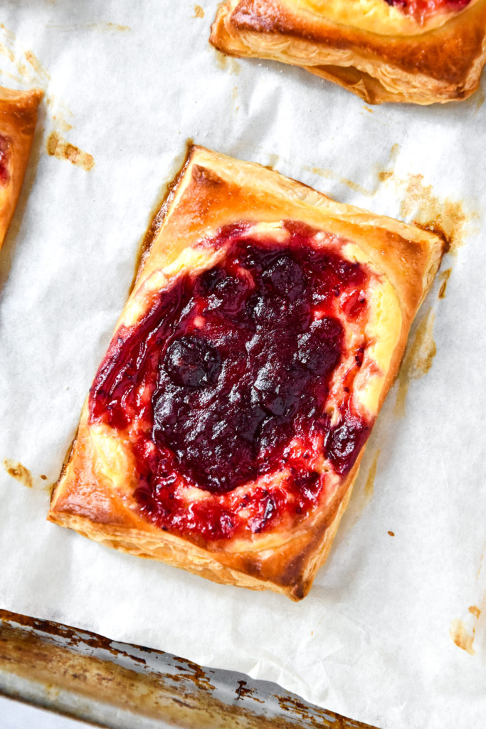 a leftover cranberry sauce cheese danish fresh out of the oven on parchment paper.
