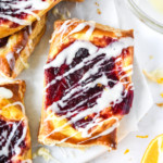 Leftover cranberry sauce cheese danish with icing on a white cutting board.