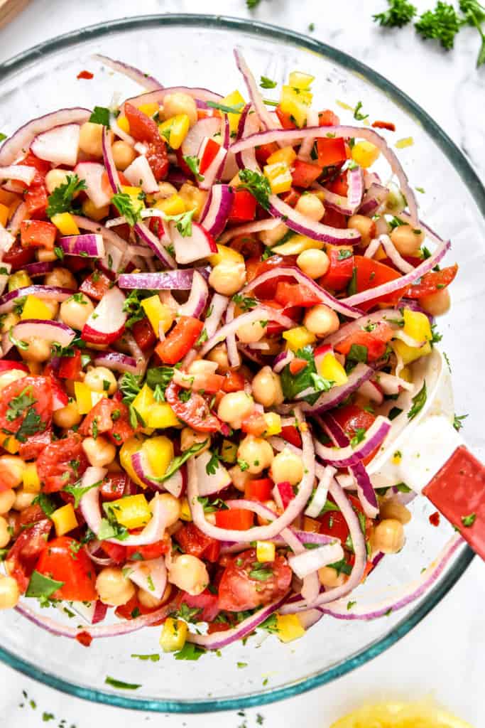 make-ahead vegan chickpea salad in a glass bowl with rubber spatula.