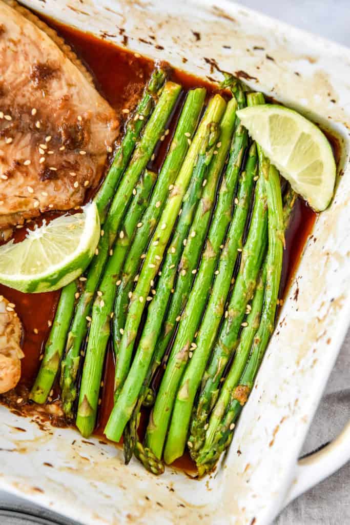 broiled asparagus in a baking dish with limes.