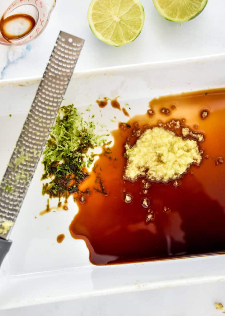 whisking ginger and lime with soy sauce in a shallow baking dish.