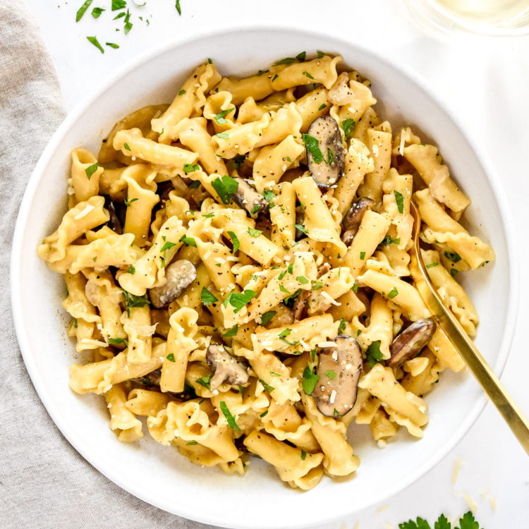 one pot creamy mushroom pasta in a white bowl with gold fork.