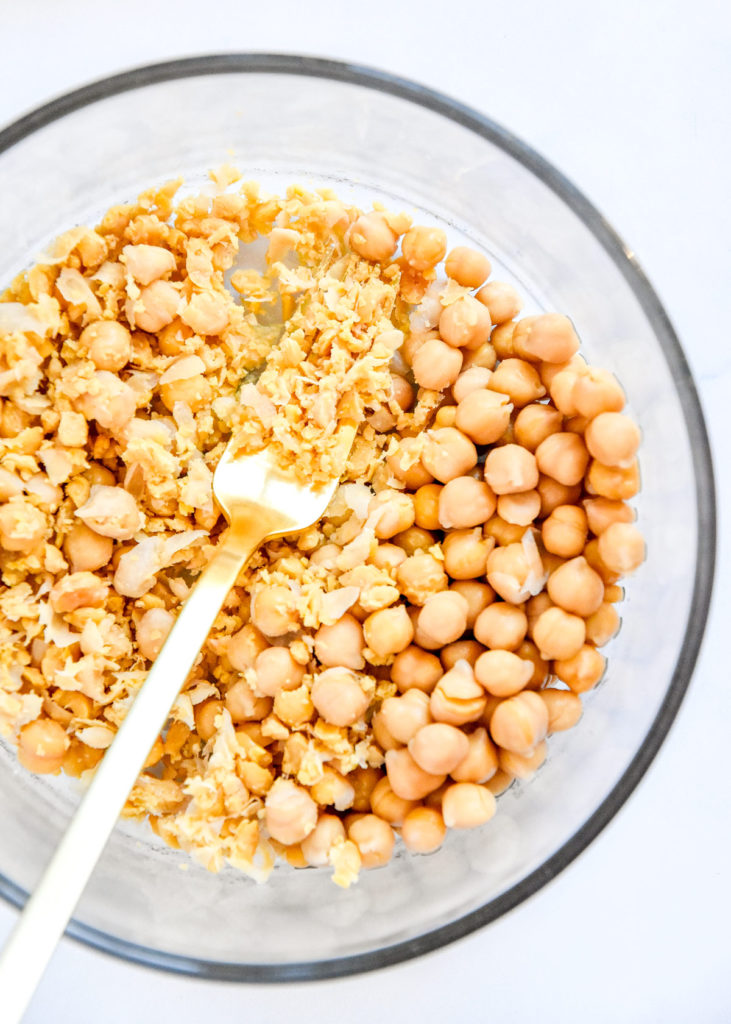 mashing chickpeas in a bowl with a fork.