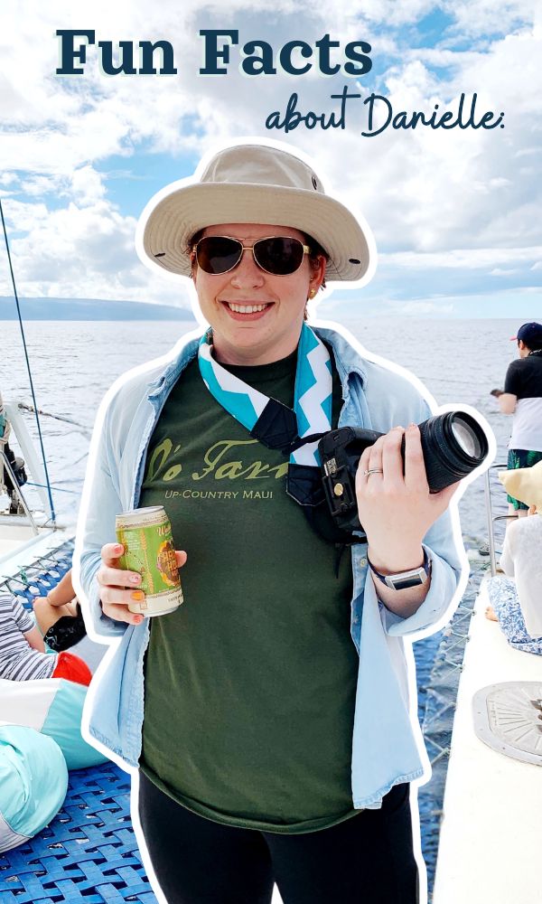 sunny day with woman standing on boat with camera and beer in hand.