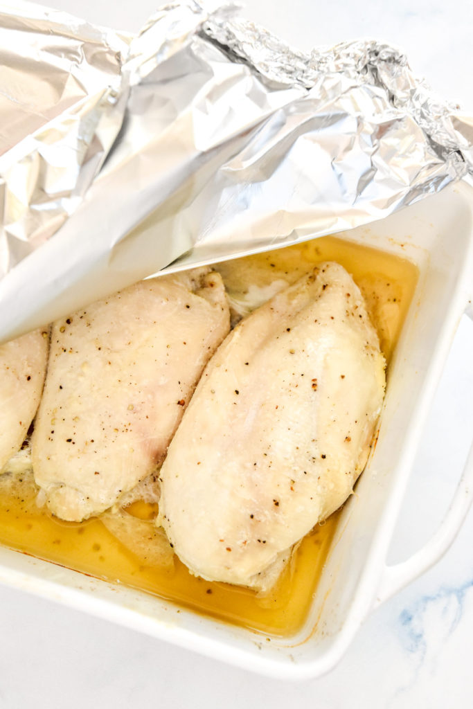 Taking the foil off the pan of the baked shredded chicken base recipe.