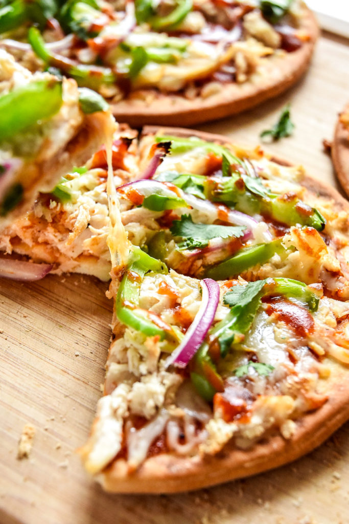 picking up a piece of pizza with peppers and onions from a cutting board.