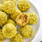 Pistachio Date Energy Balls with green coating on a white plate.