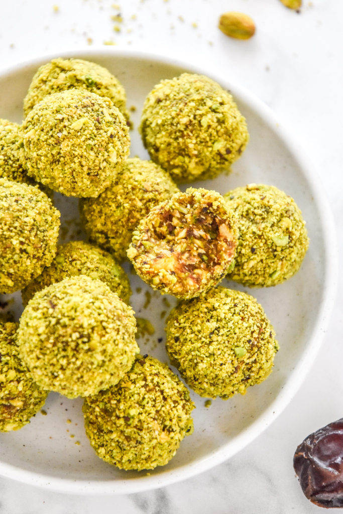 Pistachio Date Energy Balls with green coating on a white plate.