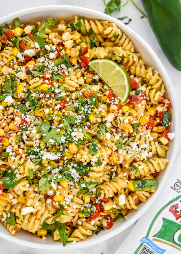 bowl of pan roasted corn pasta salad with lime, cilantro and cotija on top.
