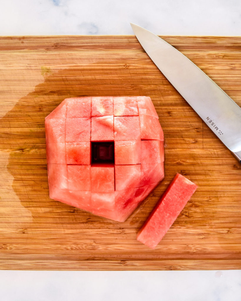 cutting watermelon into spears in a cutting board.