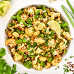 chili lime roasted cauliflower salad in a bowl with cilantro and cashews on top.