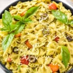 easy pesto pasta salad with fresh basil leaves on top.