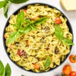 pesto pasta salad in a serving bowl with basil leaves on top.