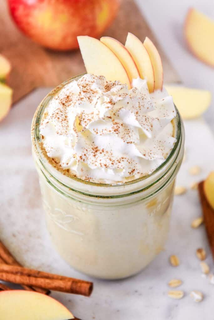 cozy apple pie smoothie with whipped cream and apple slices on top.