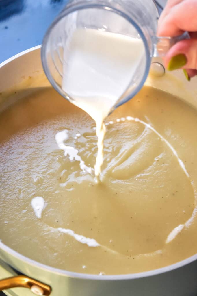 pouring some cream into the soup.