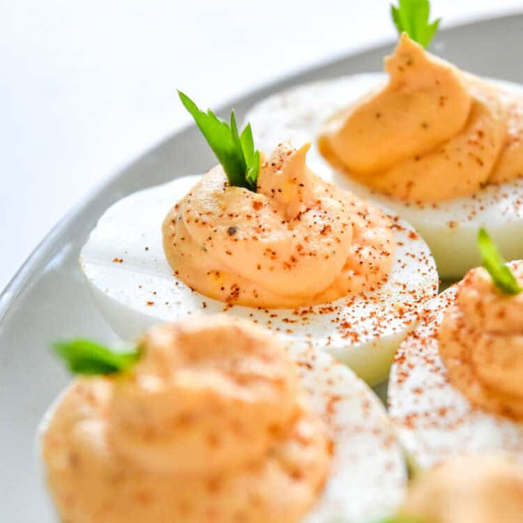 Buffalo deviled eggs with celery green sprig and paprika on top.