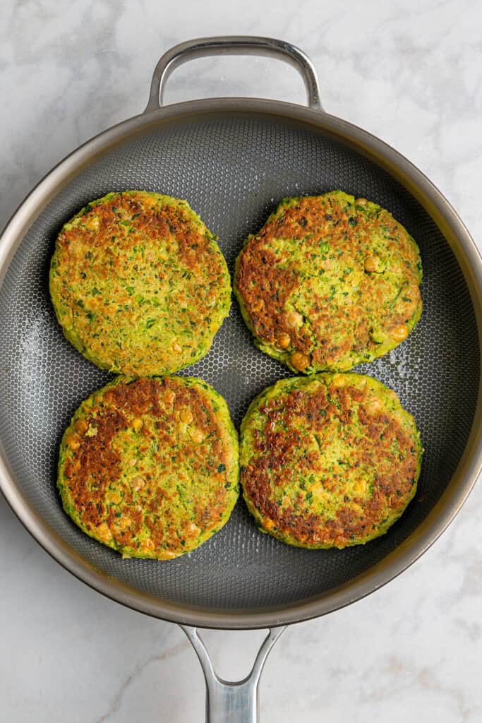 cooked herby chickpea veggie burgers in a nonstick pan.
