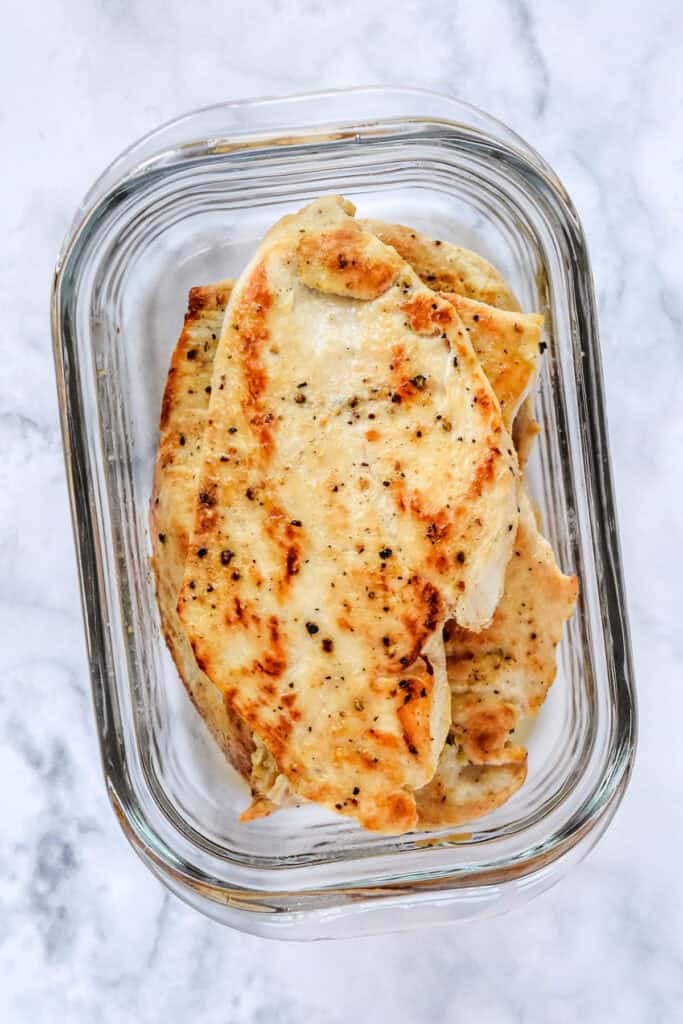 cooked and browned thin sliced chicken breast in a glass meal prep container.