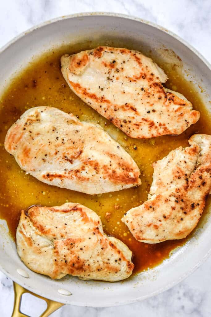 cooked and browned thin sliced chicken breast in a pan.