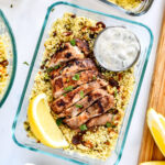 moroccan inspired spiced chicken couscous bowls with yogurt sauce and lemon wedge.