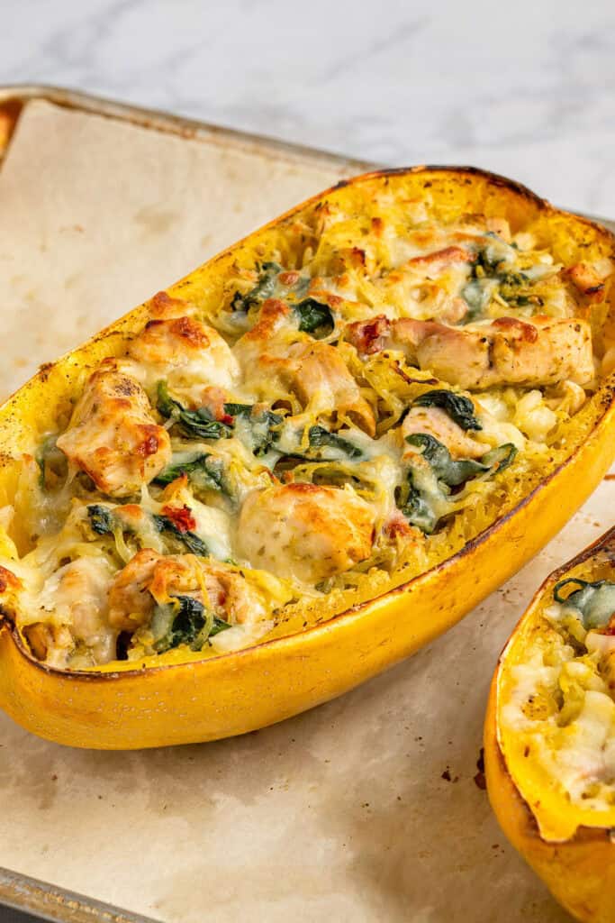 baked pesto chicken stuffed spaghetti squash with golden brown cheese on top.
