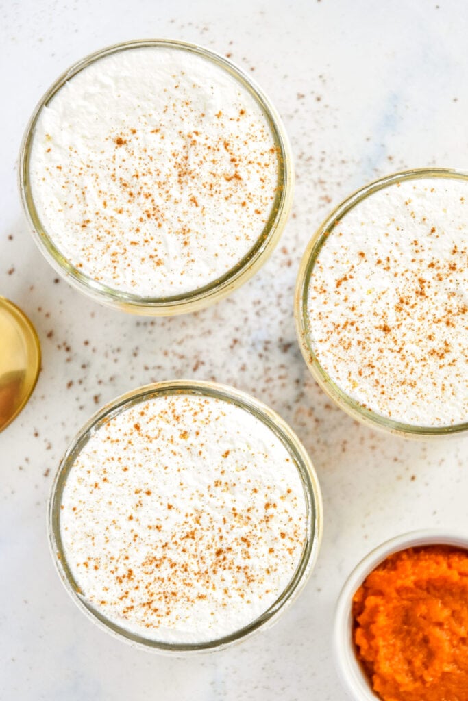 pumpkin spice whipped greek yogurt in individual glass mason jars with whipped cream.
