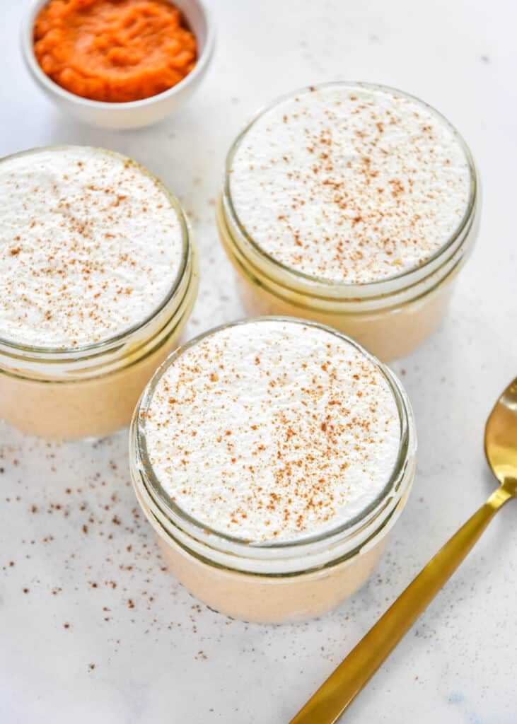 pumpkin spice whipped greek yogurt in individual mason jars with whipped cream.